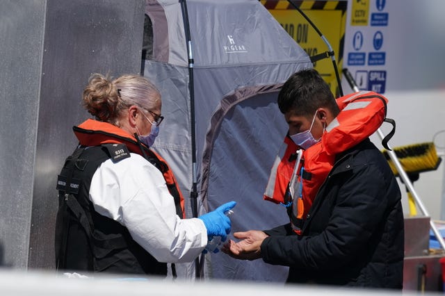 A man is given hand sanitiser by a Border Force officer as a group of people thought to be migrants are brought in to Dover, Kent, on board a Border Force vessel, following a small boat incident in the Channel 