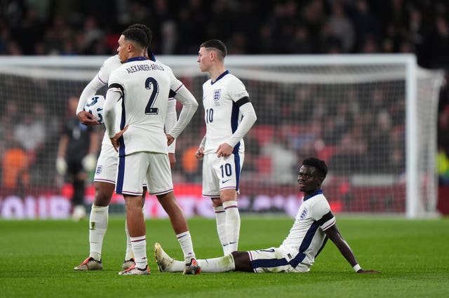 Bukayo Saka, right, sits on the Wembley turf after picking up an injury during England's defeat to Greece