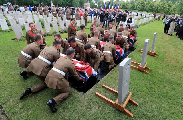 Soldiers carry the coffins of two young privates and an unknown soldier, who fought during the First World War, during a burial service at Hermies Hill British Cemetery, near Albert, France 
