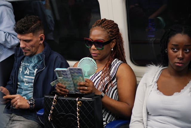 A commuter with a portable handheld fan on a Jubilee line train in London