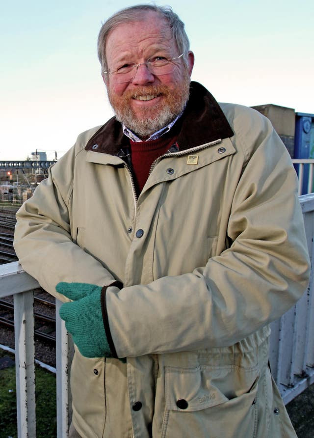 Author Bill Bryson stands next to the train tracks 