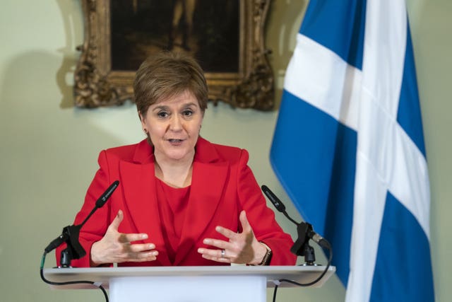 Nicola Sturgeon speaking from a lectern, with a Scottish flag behind her