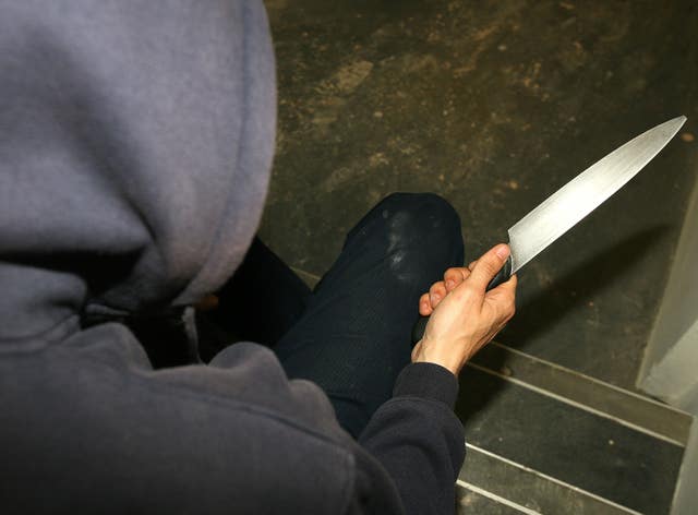 A man wearing a hoodie holding a knife