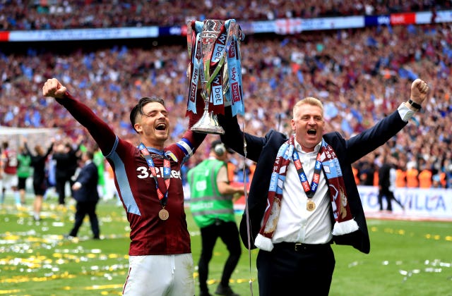 Dean Smith, right, and captain Jack Grealish lift the Championship play-off trophy
