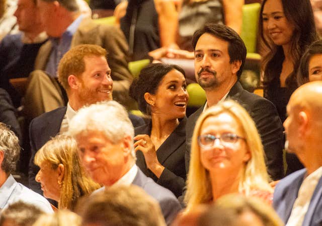 Harry and Meghan take their seats beside Lin Manuel Miranda