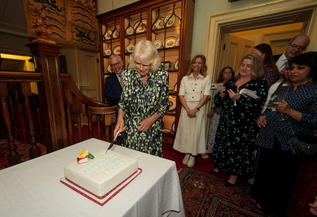 Queen Camilla cuts a cake to celebrate the National Literacy Trust charity’s 30th anniversary at Clarence House in London