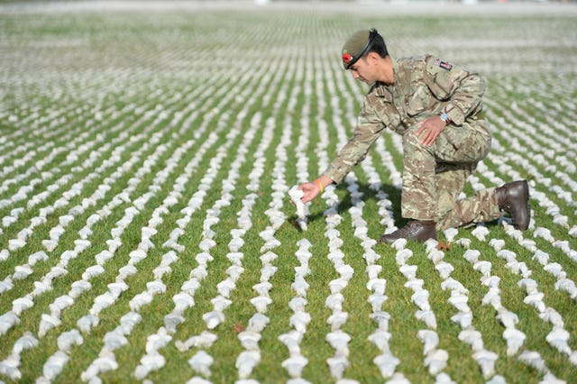 Captain James Pugh places a figure among artist Rob Heard’s installation Shrouds of the Somme