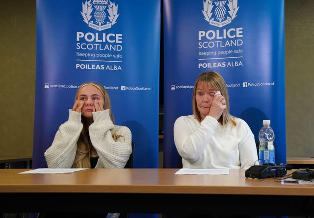 Calley Smith and Nicola Neil wiping their eyes, in front of Police Scotland signage