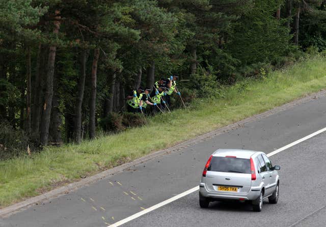 Police officers search the scene of the crash at junction nine of the M9