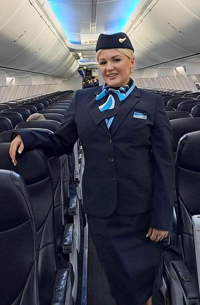 A woman standing in an empty plane in a flight attendant's uniform