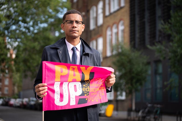 Daniel Kebede holding a sign which says 'Pay up'