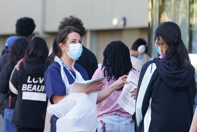 Students wait in line at the entrance to the sports hall at the University of Kent campus in Canterbury