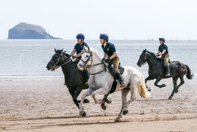 Members of the Household Cavalry, Blues and Royals, exercise their horses along the sands and in the sea at Yellowcraig Beach near North Berwick, East Lothian