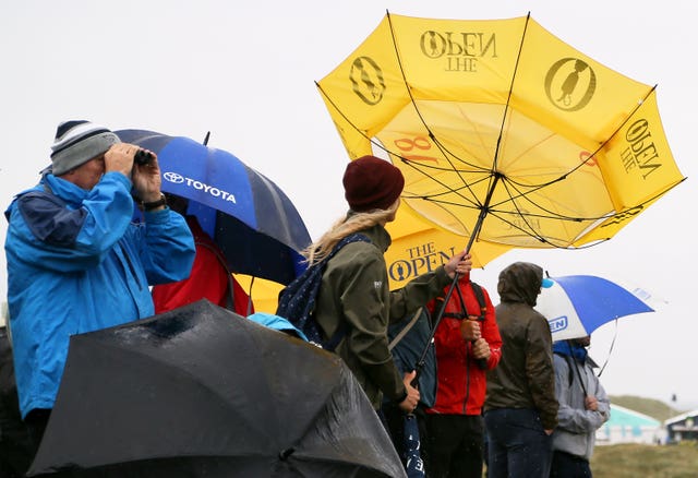 A spectator tries to adjust their inside-out umbrella 