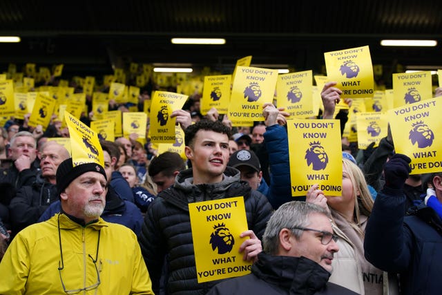 Everton fans hold posters criticising the Premier League