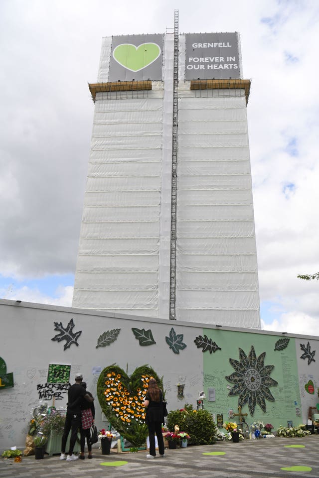 People at the Grenfell Memorial Community Mosaic at the base of the tower block (Kirsty O'Connor/PA)