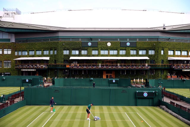 Ground staff paint the lines on the outside courts ahead of day one of the Wimbledon Championships