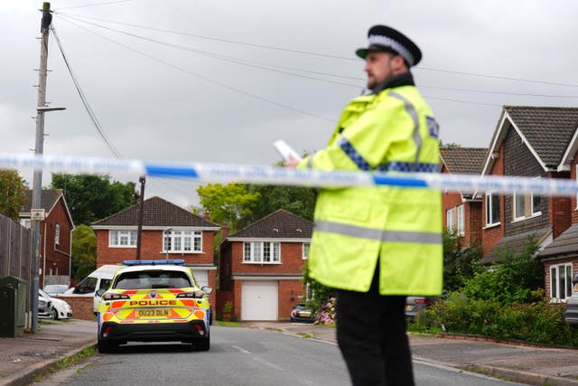 A police officer standing side-on in front of cordon tape at the scene in Ashlyn Close, Busheyr