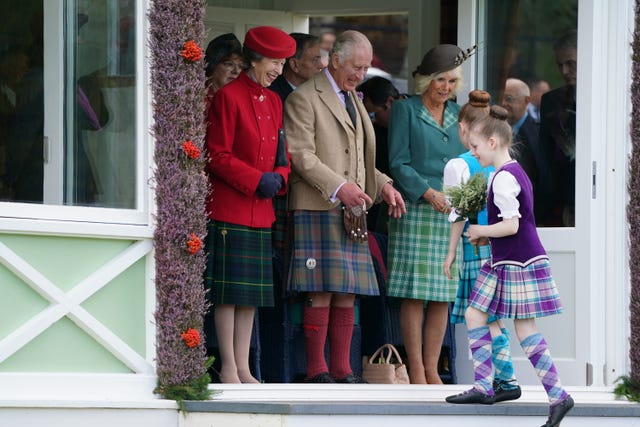 A young Highland dancer presents flowers to the royal party