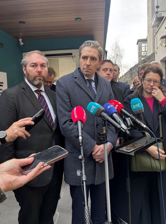 Simon Harris speaks into a number of microphones 