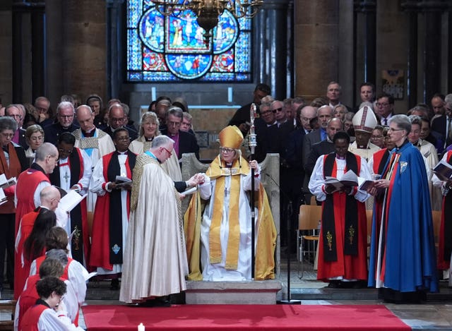 Dean of Canterbury, the Very Rev Dr David Monteith, installs the Archbishop of Canterbury, Dame Sarah Mullally, seated in the Chair of St Augustine 