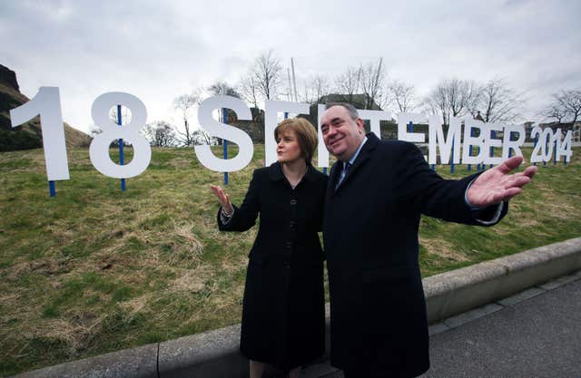 Then-first minister Alex Salmond and Deputy First Minister Nicola Sturgeon walk past a sign showing the date for the Scottish independence referendum in 2014 (PA)