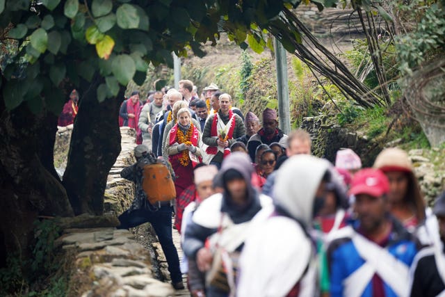 The Duke and Duchess of Edinburgh walk along a path surrounded by villagers 