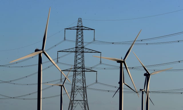 Wind turbines and electricity pylons under blue skies