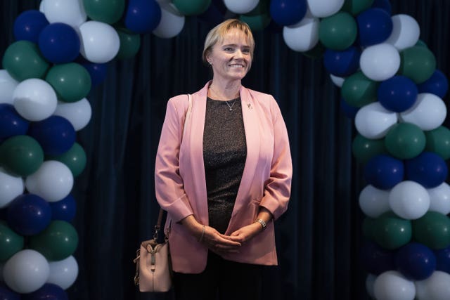 Sandie Peggie smiling, with a balloon arch behind her