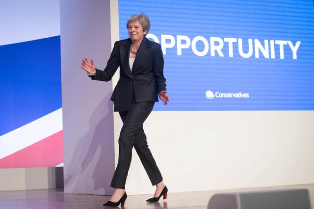 Theresa May dancing in front of Conservative signage