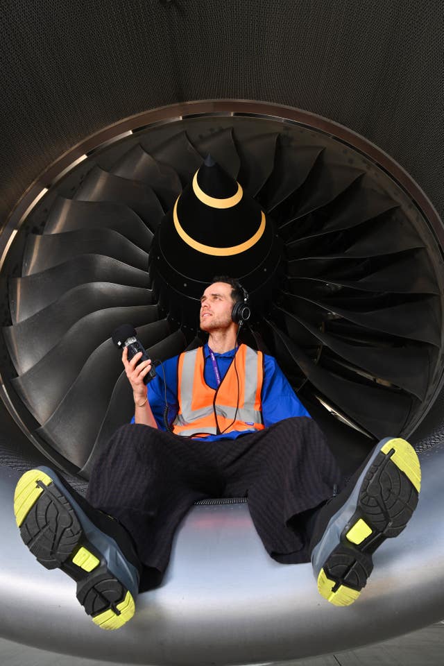 Jordan Rakei sitting next to a plane engine