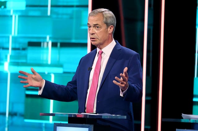 Nigel Farage behind a podium holds his hands apart while speaking