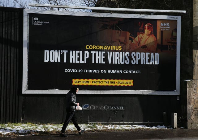 A person walks past a Coronavirus-related advert on a billboard in Falkirk