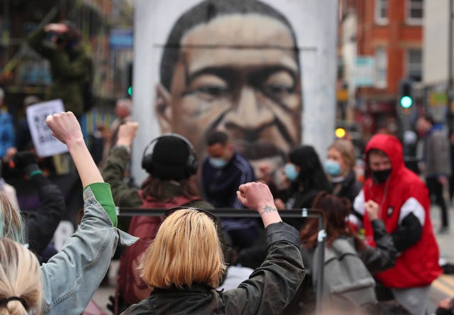 Black Lives Matter demonstrators take a knee in front of a mural of George Floyd in St Peter’s Square, Manchester