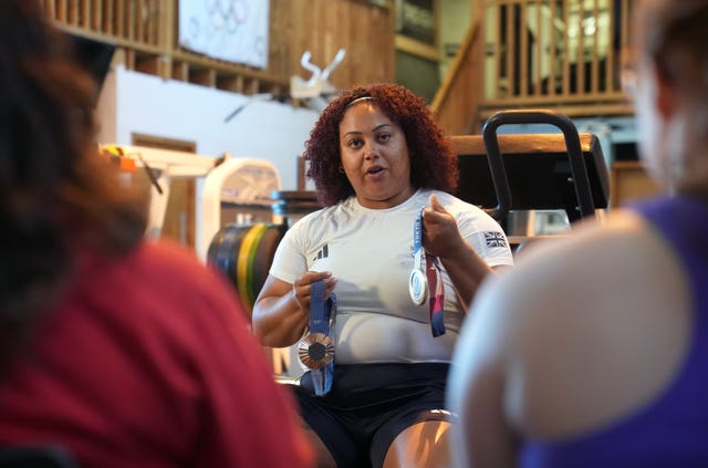 Emily Campbell shows off her medals while people sit and listen to her talk