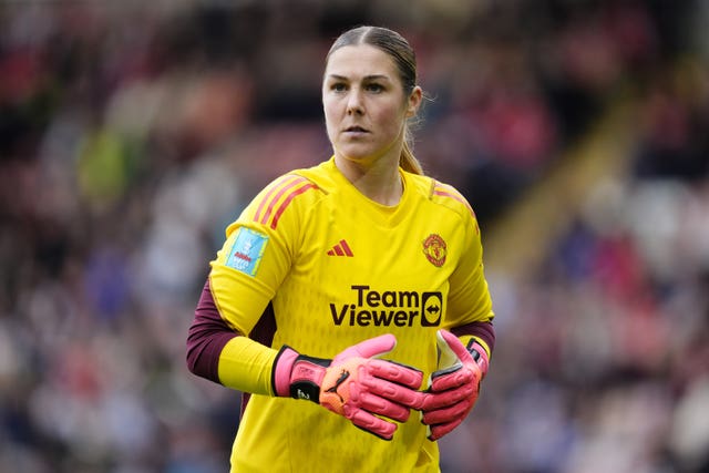 Manchester United keeper Mary Earps, wearing a bright yellow shirt and pink gloves, stares intently off to the left
