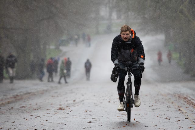A man cycles through the snow in Greenwich Park, London