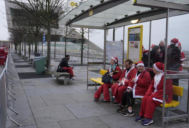 Santas enjoy a seat on a public transport bench