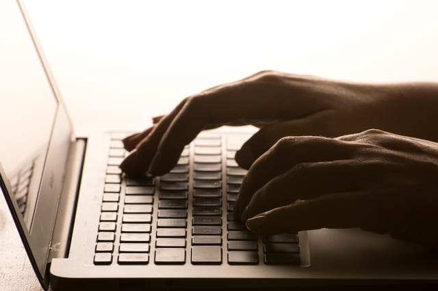 Hands on a laptop keyboard.