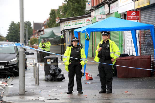 Police officers stand at the cordoned off area in Claremont Road, Moss Side 