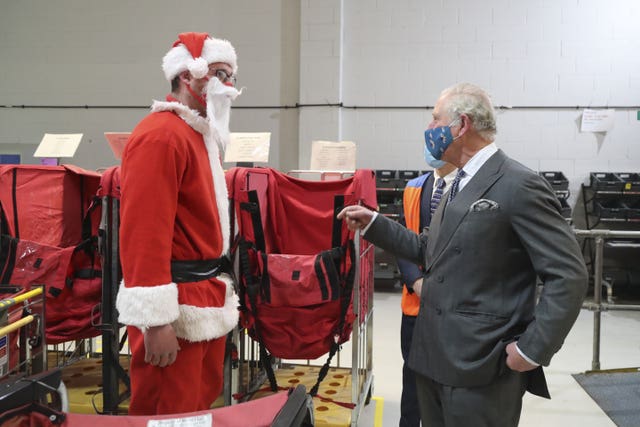 Charles speaks to postal worker Tim Lafford dressed in a Father Christmas outfit. Geoff Caddick/PA Wire