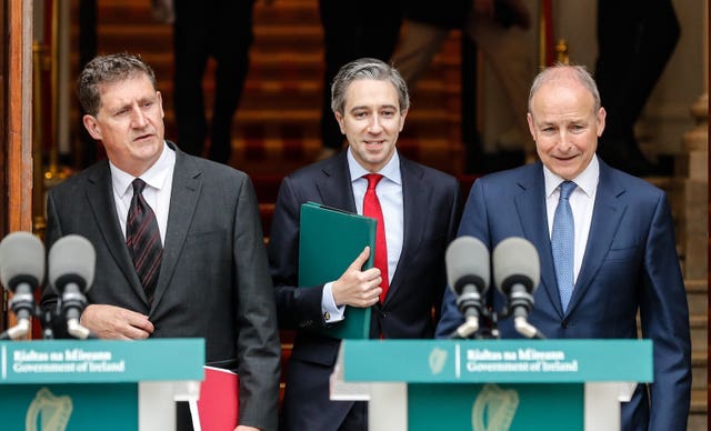 Minister Eamon Ryan (left), Taoiseach Simon Harris (centre) and Tanaiste Micheal Martin standing behind podiums