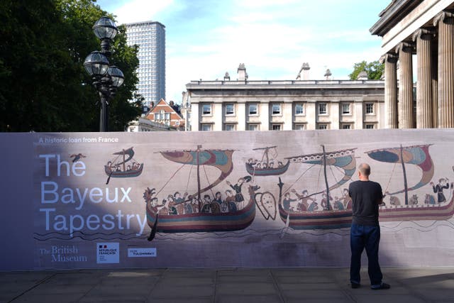 A visitor looks at hoarding which highlights the Bayeux Tapestry Exhibition at the British Museum in London