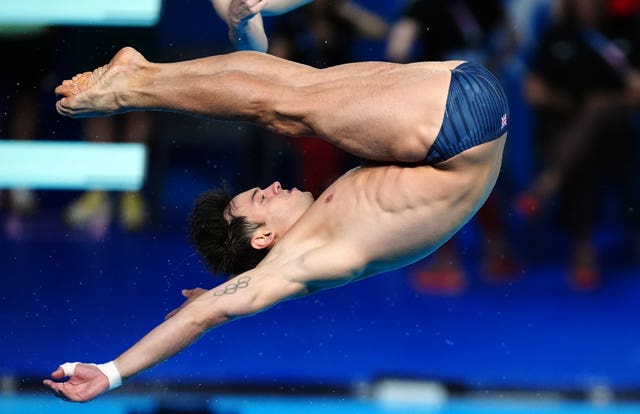 Tom Daley mid-dive with his arms outstretched and legs over his head