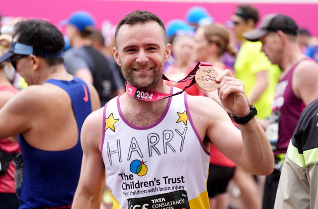 Harry Judd in a Children's Trust T-shirt holding up his London Marathon 2024 medal