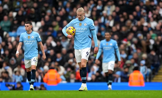 Erling Haaland holds a ball under his arm and looks dejected after Manchester City concede a goal