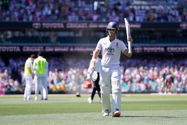 England's Jacob Bethell walks off the ground and raises his bat after being dismissed for 154 in Sydney