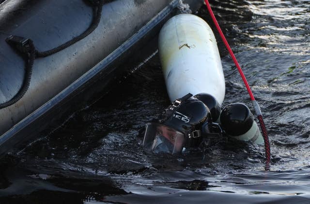 Police diver in water, next to small boat