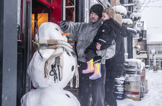 Christian Ogley with his daughter Noa make a snowman in Knaresborough, North Yorkshire 