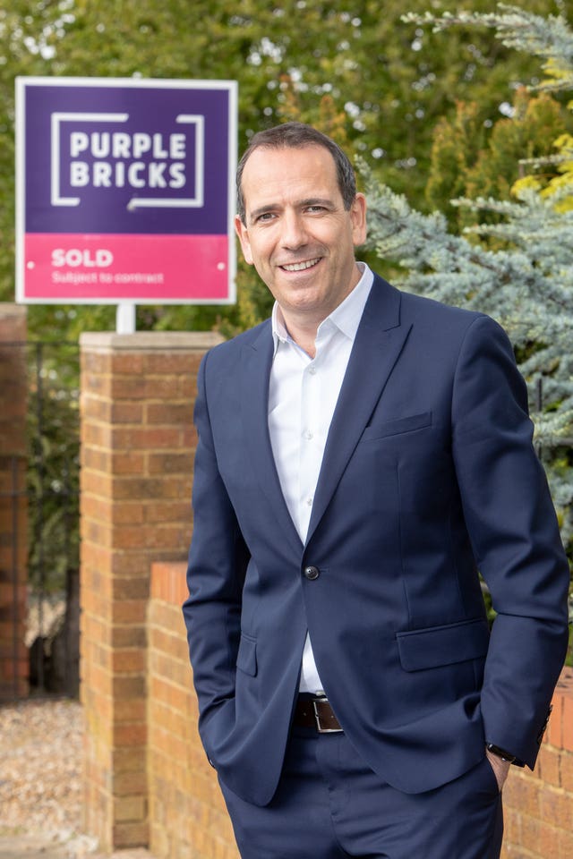 Purplebricks boss Vic Darvey standing by a For Sale sign.